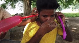 Man blows two balloons from ear in Central East India.