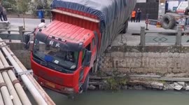 Truck hangs over riverbank after crashing through guardrails in China