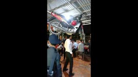 Vietnamese street performer balances motorbike on his head while dancing