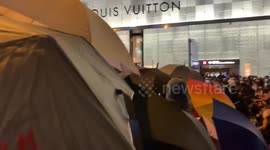 Masked protesters pull back as riot police raised the blue flag