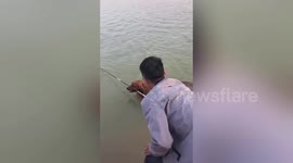 Golden retriever brings fishing rod back to man after fish dragged it away