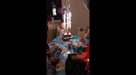 The boy tries to put out the small firework by blowing into it