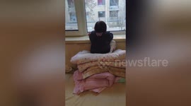 Chinese toddler lies on window ledge for hours watching cartoons on TV in opposite building