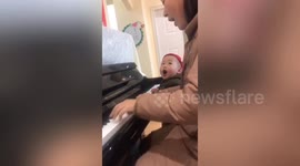 Two-year-old boy sings along with his mum playing the piano