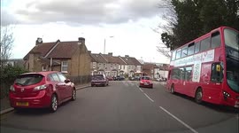 Kids run out from behind a bus in front of a learner car forcing them to do an emergency stop