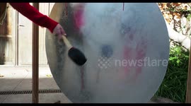 a large metal drum gong hit with mallet with sound