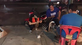 Three Men Charge Their Phones With Street Cable