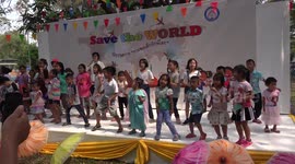 Amazing energetic children dancing on stage at a children's day party at a Buddhist temple grounds, in Thailand.