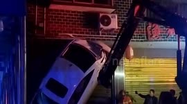 Chinese firefighters rescue motorist trapped inside car stuck vertically on shop gates