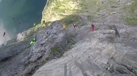 Mesmerising moment troop of 26 base jumpers leap from Norwegian cliff face in formation