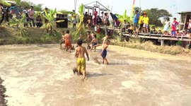 Thai children catch snakehead fish from muddy pool at village festival