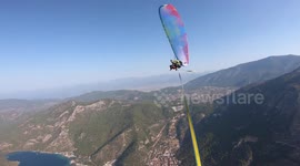 Parachuter balances on a slackline that is tied in mid air between two paragliders