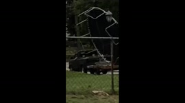 Driving trampoline on trailer while standing up across town