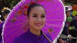 Beauty contestants parade on bicycles while holding umbrellas