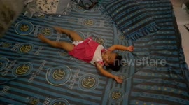 A 19-month-old girl rolling on a mattress