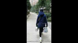 Foreign workers stuck in Wuhan carry food supplies back to room