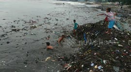 Children seen playing in tide of plastic waste washing up on Indonesian beach