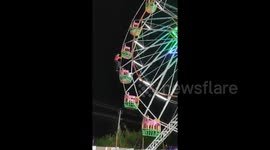 India fairground staff perform nerve-wracking stunt by hanging onto Ferris wheel as it spins around at speed