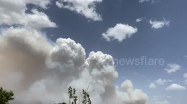 Helicopter flys through fire smoke and building weather clouds south of nation’s capital