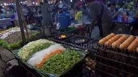 A Thai chef cooking some hot oyster omelettes at a temple fair in Thailand, he is almost engulfed in a wall of flames.