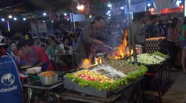 Busy Thai chefs cooking at a Thai temple fair, in Thailand and creating a wall of flames.