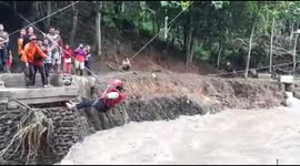 Indonesian residents use ropes to cross river after flooding destroys bridge