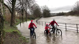 Plucky family cycle through swollen river in Cumbria during Storm Ciara