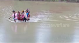 Family members carry pregnant woman on sling across river