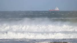 Tanker Ship Anchored At Sea As Storm Denis Delivers Large Breakers On Beach