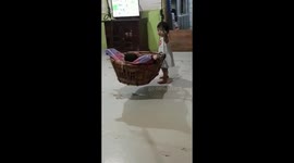 Role reversal: Cute scene as baby sis puts big brother to sleep in swinging basket