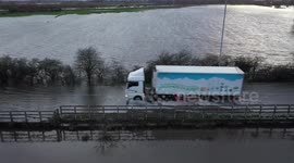 Vehicles plough through streets submerged by floodwater in northern UK