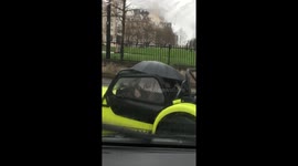 Convertible driver uses an UMBRELLA to keep dry in the rain