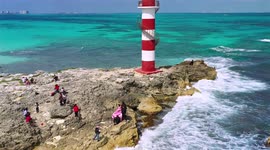 Aerial footage of people taking pictures seaside by a lighthouse
