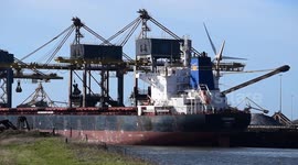 Coal unloading from ship with windmill in the background