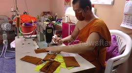 Buddhist monks sew orange face masks that match their robes to protect against coronavirus