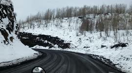 View from a semi truck as it descends a snowy mountain from a coal mine in winter conditions.