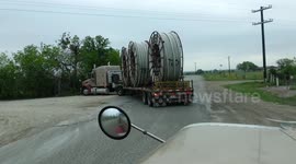 An American semi truck hauling reels of HDPE plastic pipe on a flatbed trailer for the oil industry and fracking sites in the USA