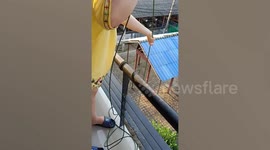 Quarantined workers back from South Korea have food delivered by buckets on ropes in Thailand