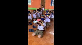 Thai schoolchildren take part in hilarious game passing plates full of flour over their heads