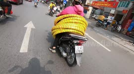 Vietnamese woman controls a motorbike with dozens of tires wrapped around her body