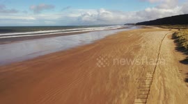 Pretty aerial view of sand blowing across Northern Ireland beach