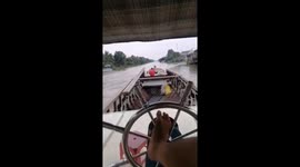 The man used his feet to control the rudder of a large boat moving on the river