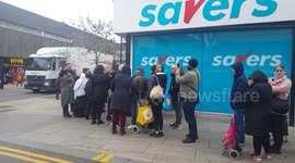 Customers queue round corner of UK shop where toilet roll is limited to two packs per person
