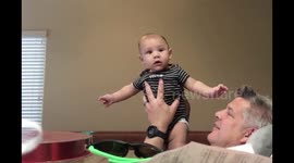 Laughing baby boy playing peek a boo sitting with dad