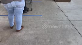 Long line to get into grocery store Vallarta market line practicing social distancing with blue tape