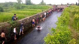 Indonesian kids use irrigation channel as water slide after heavy rain