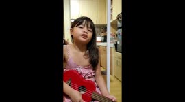 Little girl plays Ukelele on phone as project for her online class