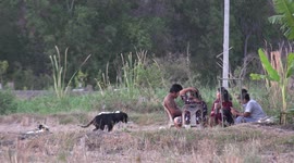 Simple living, a Thai family relaxing at sunset outside their home, on a rice farm in rural Thailand.