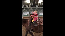 Little toddler enjoys riding a horse