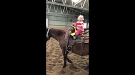 Little toddler loves to ride her horse by herself.